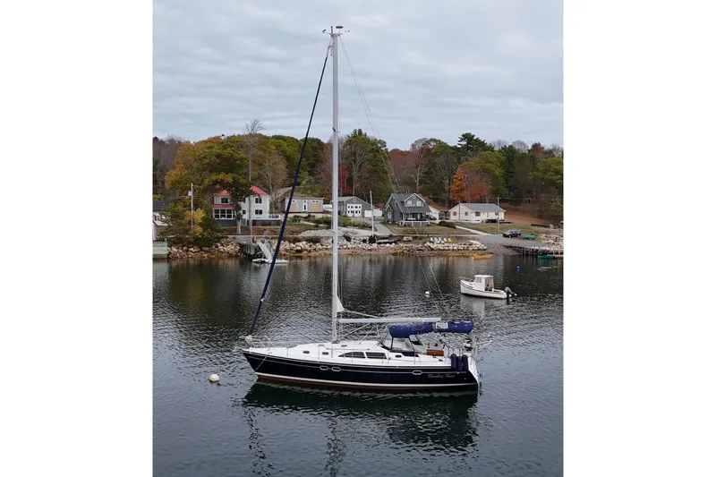 Rendez-vous Yacht Photos Pics Catalina 387 sailboat from 2003 docked in a scenic harbor with autumn trees.