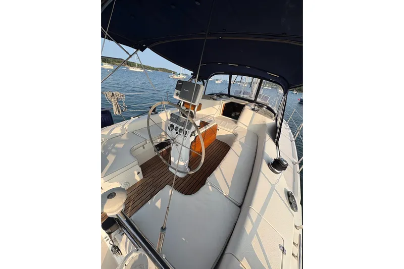 Rendez-vous Yacht Photos Pics 2003 Catalina 387 sailboat cockpit with steering wheel, wood accents, and canopy on calm water.