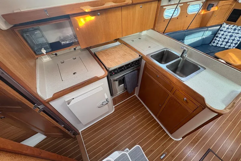 Rendez-vous Yacht Photos Pics 2003 Catalina 387 yacht kitchen with wood cabinetry, dual sinks, and compact appliances.