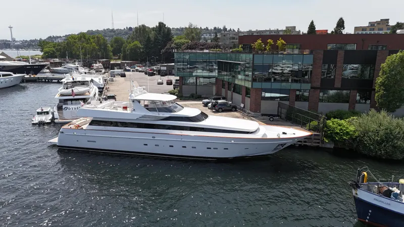 Arrivederci IV Yacht Photos Pics Luxury yacht Cantieri di Pisa AKHIR 1998 docked at marina, surrounded by modern buildings.