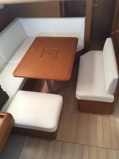 Yacht Photos Pics 2019 Jeanneau Sun Odyssey 479 interior with wooden table and white cushioned seating.