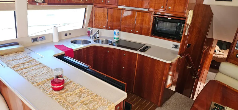 Christina Yacht Photos Pics Luxurious kitchen interior of 2004 Riviera 58 Enclosed Flybridge yacht with wood cabinetry.