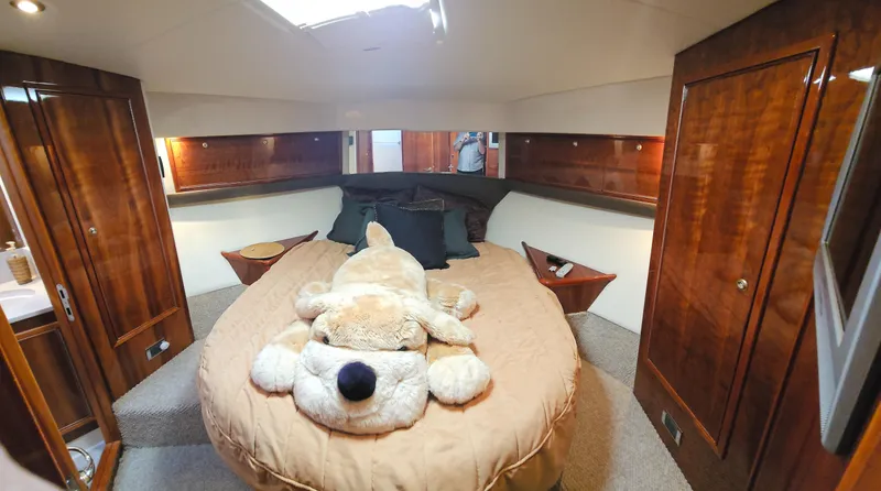 Christina Yacht Photos Pics Luxurious 2004 Riviera 58 Enclosed Flybridge bedroom with plush decor and wooden cabinetry.