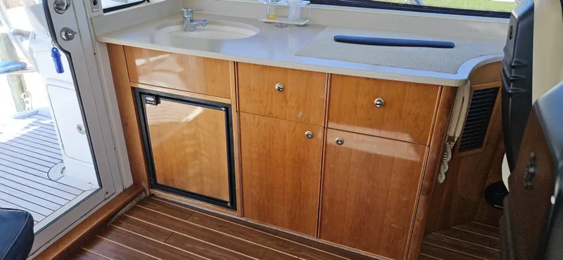 Christina Yacht Photos Pics 2004 Riviera 58 Enclosed Flybridge interior with wooden cabinetry and compact sink area.