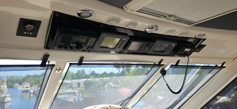 Christina Yacht Photos Pics Interior view of 2004 Riviera 58 Enclosed Flybridge with navigation equipment and waterfront background.