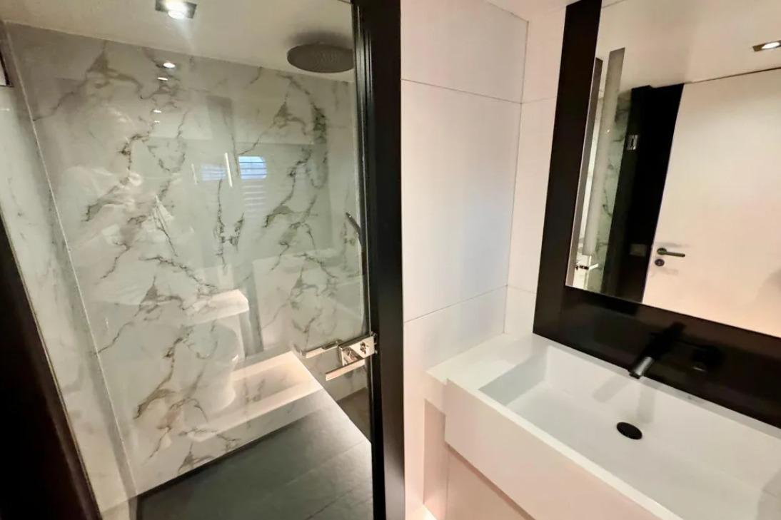 Modern bathroom with marble shower and sleek white sink, 2024 Explorer ICE model.