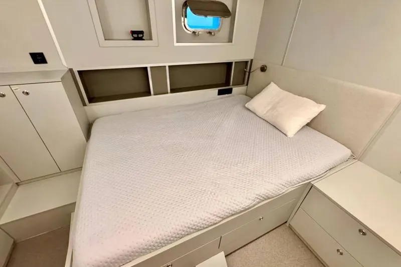  Yacht Photos Pics 2024 Explorer ICE yacht bedroom with modern design, white bedding, and storage cabinets.