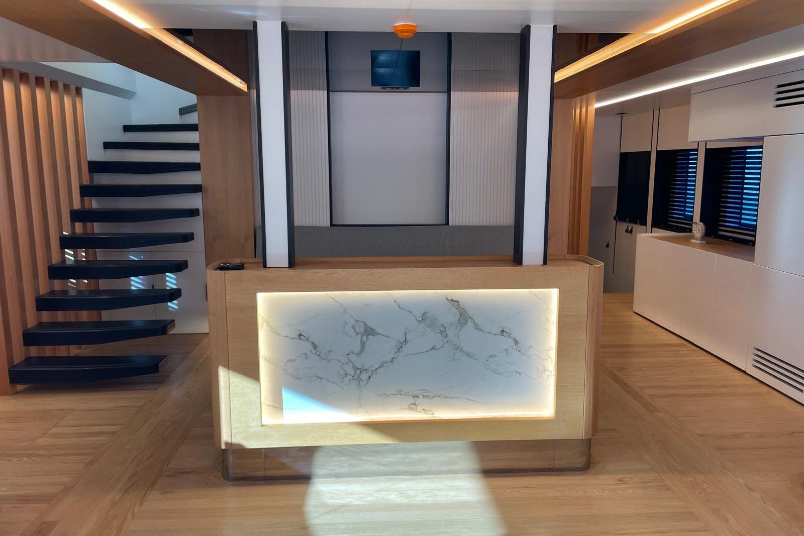 Modern interior with wooden flooring, floating staircase, and illuminated marble reception desk. Explorer ICE 2024.