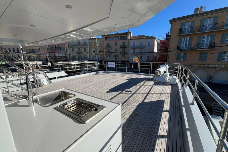  Yacht Photos Pics Spacious deck of 2024 Explorer ICE yacht with sink and grill, docked near colorful buildings.