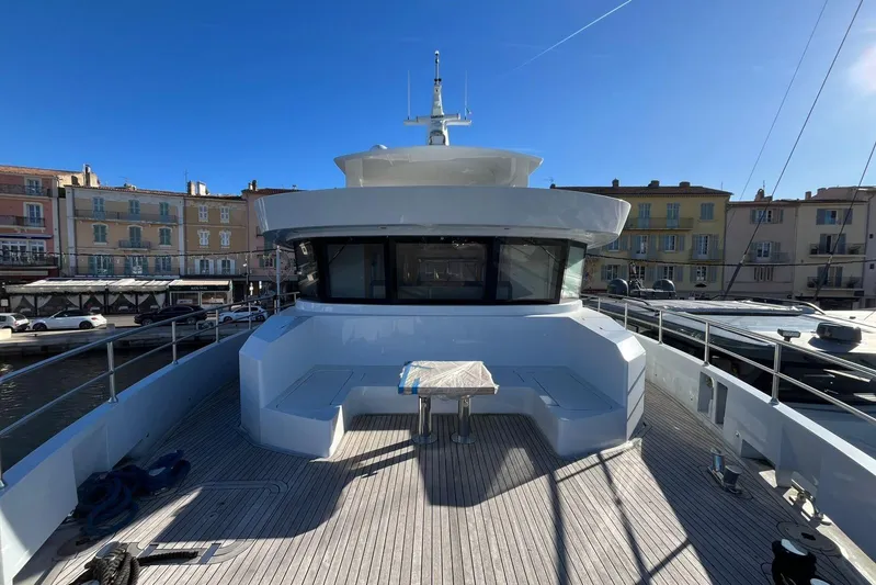  Yacht Photos Pics 2024 Explorer ICE yacht deck with seating area, docked in a sunny harbor.