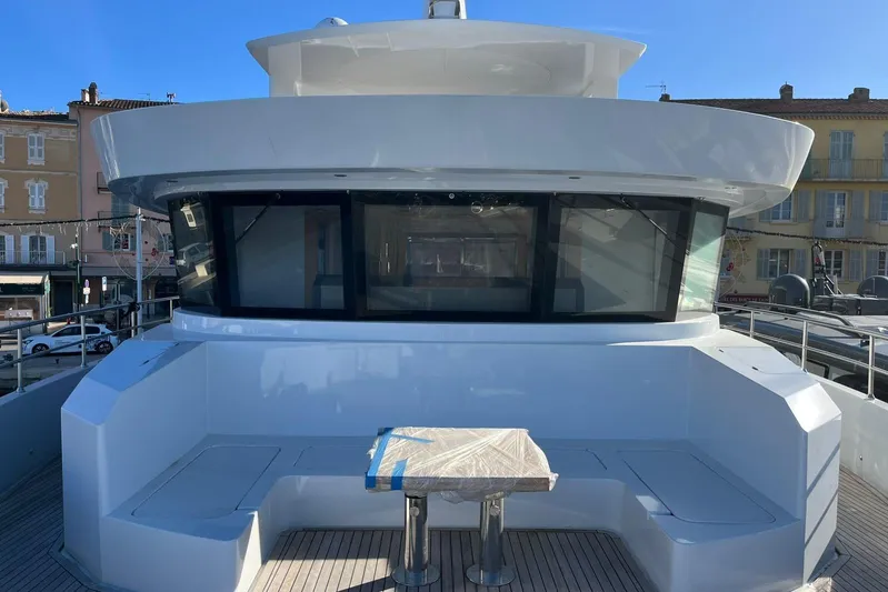  Yacht Photos Pics 2024 Explorer ICE yacht deck with seating and table, docked in a sunny harbor.