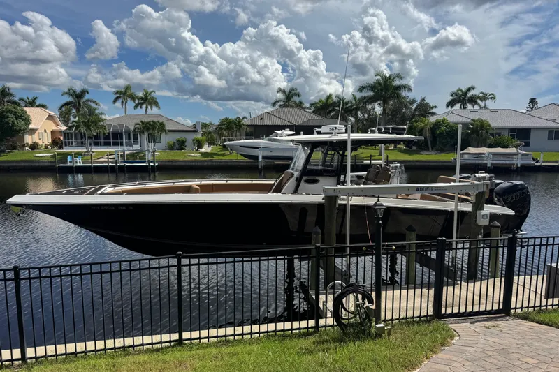  Yacht Photos Pics 2020 Fountain 38 Center Console boat docked by waterfront homes under a cloudy sky.