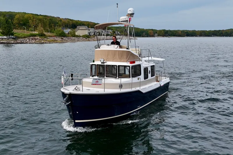  Yacht Photos Pics 2025 Ranger Tugs R-31 CB cruising on a scenic lake with lush shoreline.