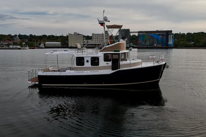  Yacht Photos Pics 2025 Ranger Tugs R-31 CB boat on calm water, cityscape background.