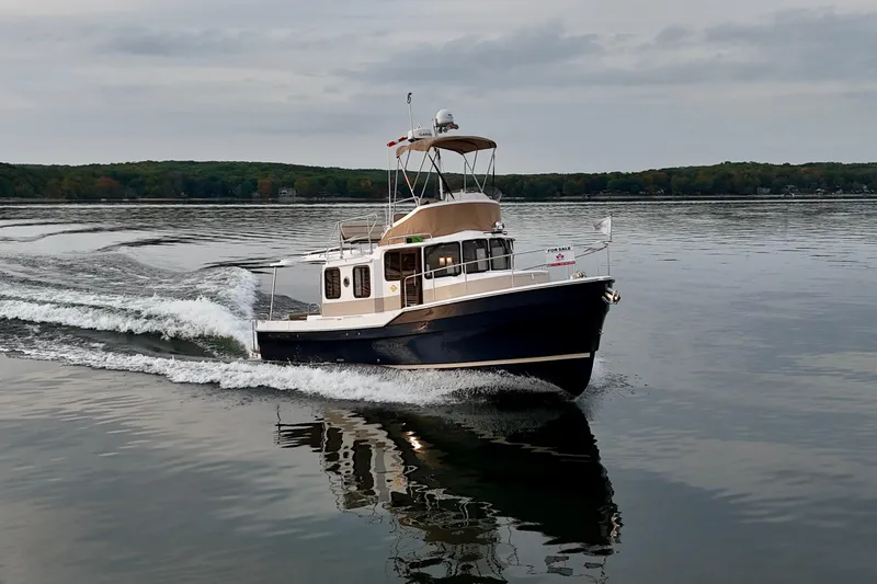  Yacht Photos Pics 2025 Ranger Tugs R-31 CB cruising on a calm lake under cloudy skies.