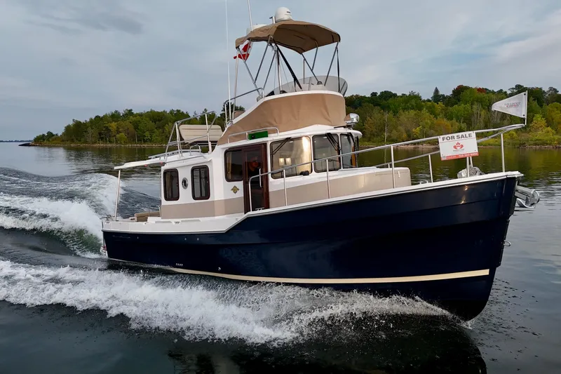  Yacht Photos Pics 2025 Ranger Tugs R-31 CB cruising on a serene lake, with a "For Sale" sign displayed.