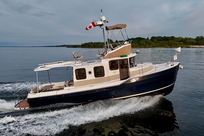  Yacht Photos Pics 2025 Ranger Tugs R-31 CB cruising on a calm lake with scenic shoreline.