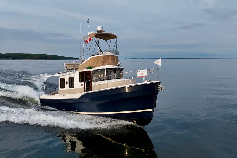  Yacht Photos Pics 2025 Ranger Tugs R-31 CB cruising on calm waters, for sale sign visible.