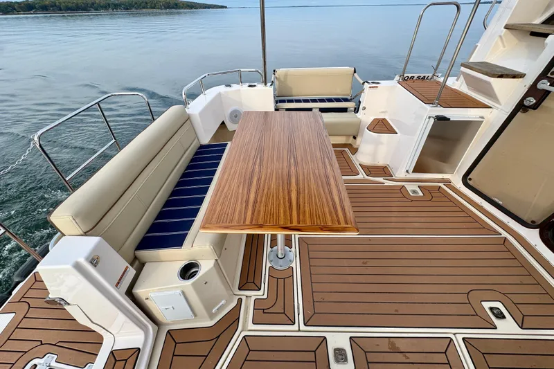  Yacht Photos Pics 2025 Ranger Tugs R-31 CB boat deck with seating and wooden table, overlooking calm water.