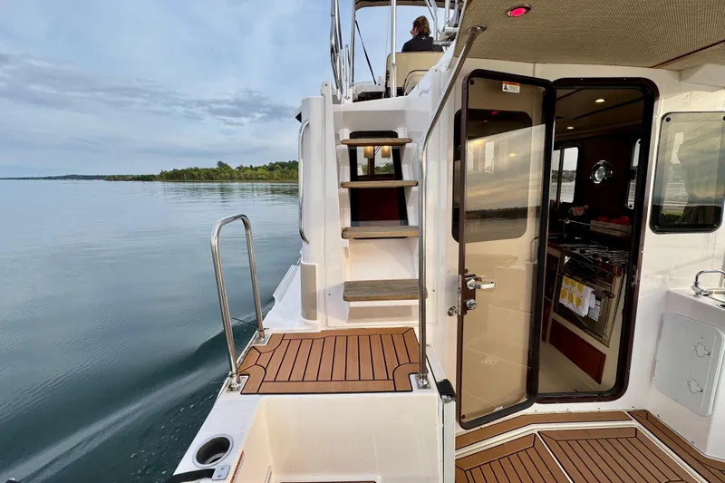  Yacht Photos Pics 2025 Ranger Tugs R-31 CB boat with open cabin door, wooden deck, and scenic water view.