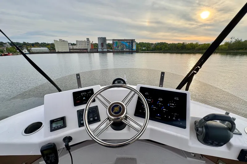  Yacht Photos Pics Cockpit view of 2025 Ranger Tugs R-31 CB, steering wheel and controls, scenic waterfront.