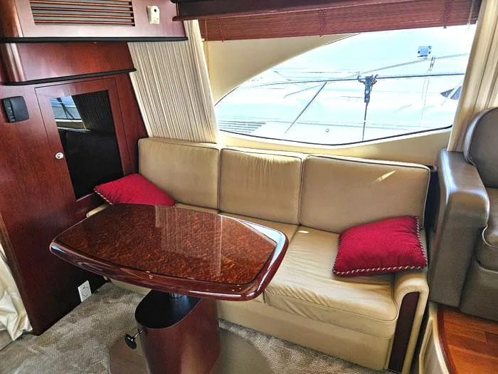  Yacht Photos Pics Luxurious interior of 2006 Sea Ray 44 Sedan Bridge with beige sofa and wooden table.