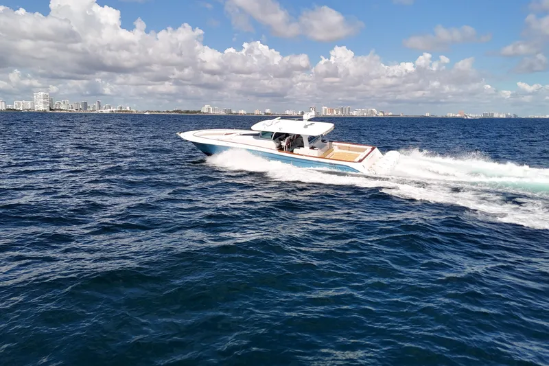  Yacht Photos Pics 2021 HCB 65 Estrella cruising on open ocean with city skyline in background.