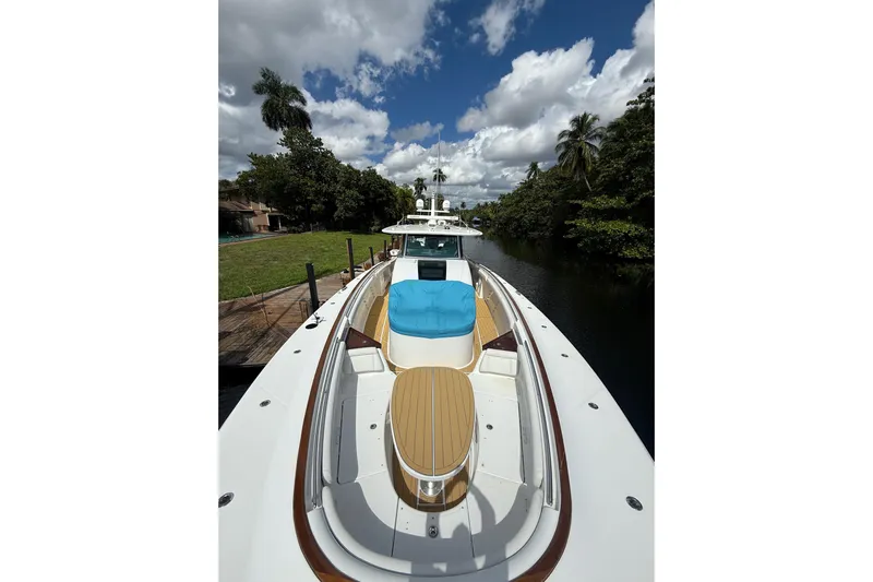  Yacht Photos Pics Luxurious 2021 HCB 65 yacht docked by lush greenery under a partly cloudy sky.