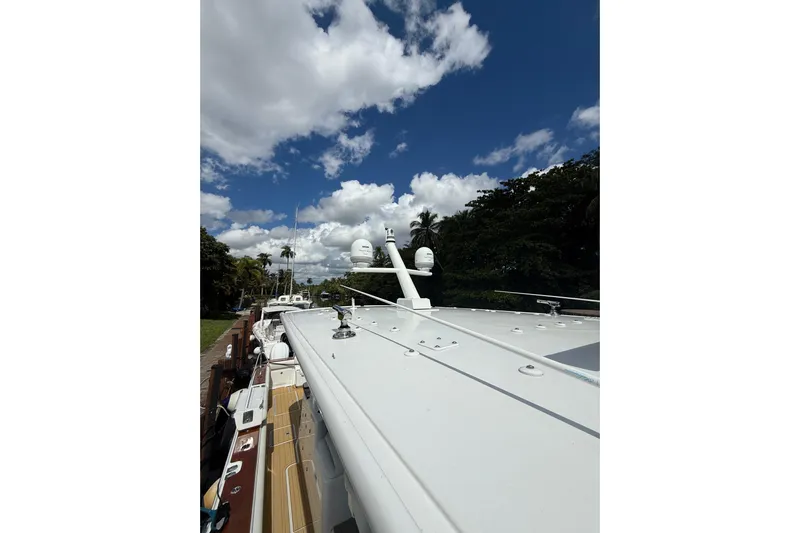  Yacht Photos Pics 2021 HCB 65 boat deck under a partly cloudy sky, surrounded by lush greenery.