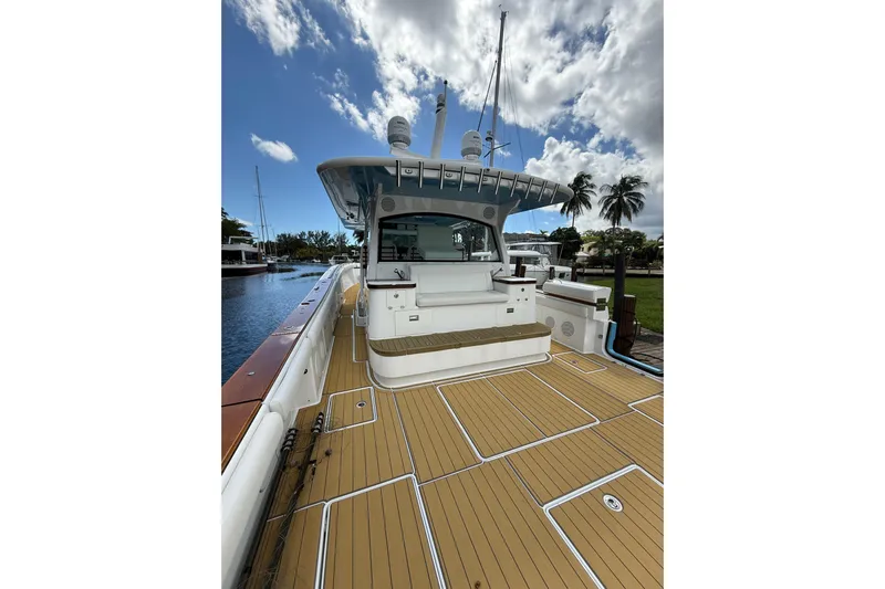  Yacht Photos Pics 2021 HCB 65 yacht with spacious deck, docked under a partly cloudy sky.