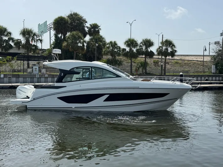 Eleven Eleven Yacht Photos Pics 2022 Beneteau Gran Turismo 32 yacht on calm water, with palm trees in the background.