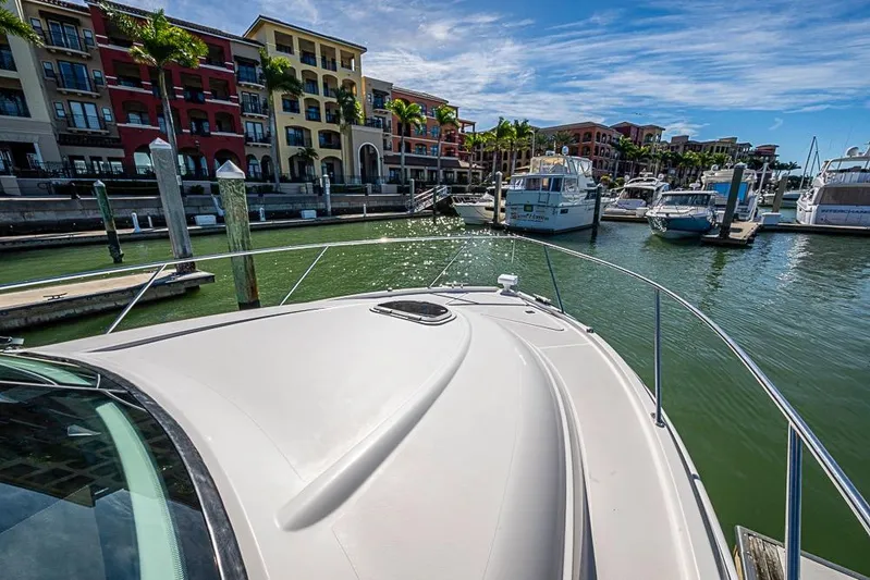 Exitevent Yacht Photos Pics 2017 Tiara Yacht Coupe docked in a vibrant marina with colorful buildings.