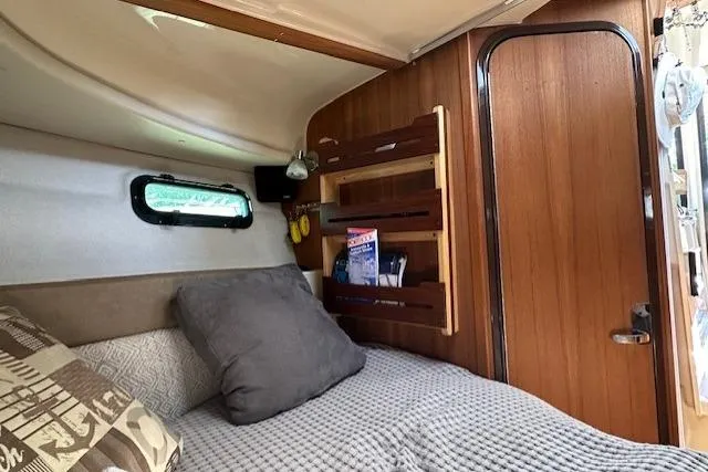  Yacht Photos Pics 2024 Ranger Tugs R-27 cabin interior with cozy bed and wooden storage shelves.