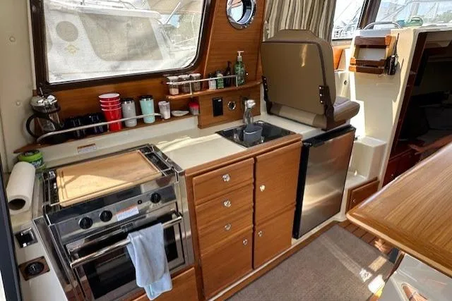  Yacht Photos Pics 2024 Ranger Tugs R-27 interior kitchen with stove, sink, and compact fridge.