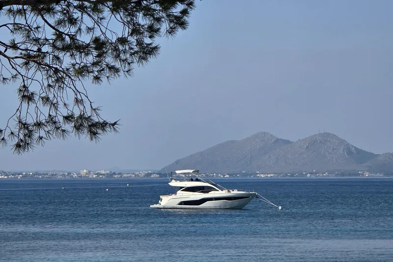  Yacht Photos Pics 2020 Cranchi E 52S Evoluzione yacht anchored in serene blue waters with distant mountains.