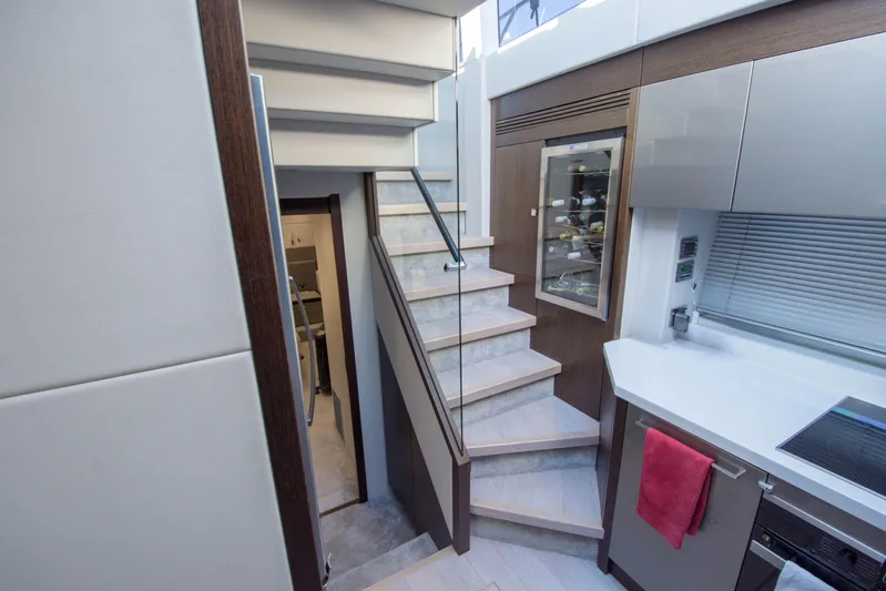  Yacht Photos Pics Modern interior of 2020 Sunseeker Predator 74 XPS yacht with sleek staircase and kitchen area.