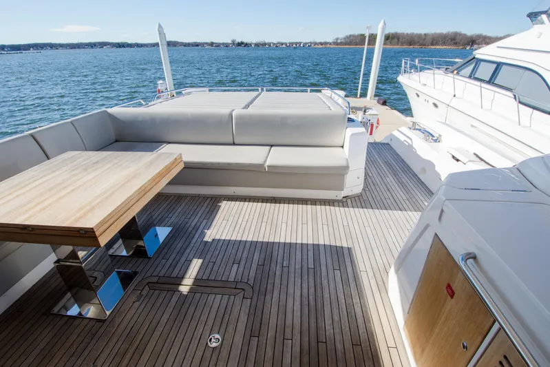  Yacht Photos Pics Luxurious Sunseeker Predator 74 XPS yacht deck with seating and table, overlooking serene waters.