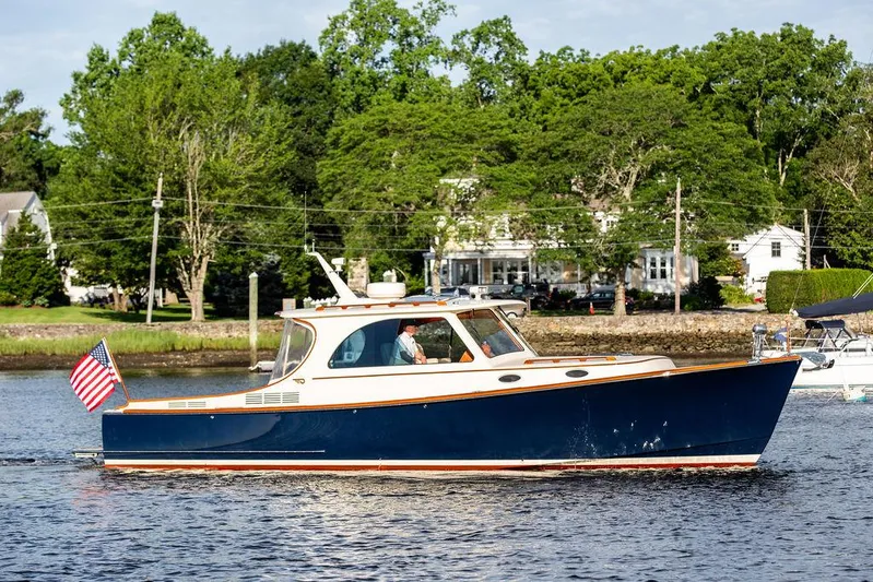 Gracious Yacht Photos Pics 2011 Hinckley Picnic Boat Mark III cruising on a serene waterway, surrounded by lush greenery.