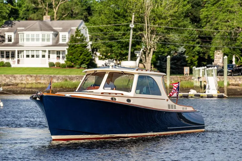 Gracious Yacht Photos Pics Hinckley Picnic Boat Mark III 2011 cruising on a serene river near a charming house.