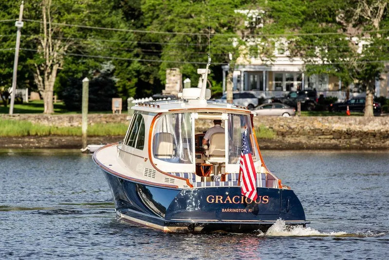 Gracious Yacht Photos Pics Hinckley Picnic Boat Mark III, 2011, cruising on a serene river with American flag.