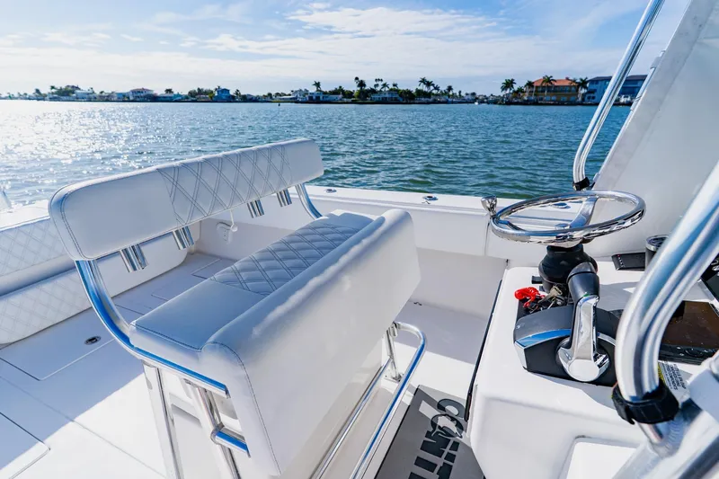  Yacht Photos Pics 2025 Contender 32 ST boat interior with steering wheel and seating, overlooking calm waters.