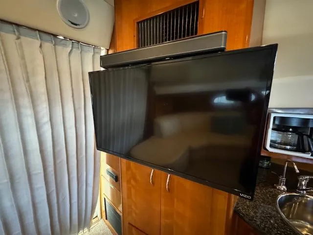 Why Knot Yacht Photos Pics 2003 Carver 410 Sport Sedan interior with TV, sink, and wooden cabinetry.