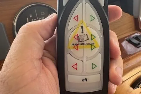 Figur'in It Out Yacht Photos Pics Hand holding a remote control with directional buttons, labeled "READ INSTRUCTIONS," on a Mainship 400 Trawler.