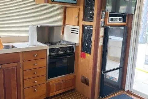 Figur'in It Out Yacht Photos Pics 2006 Mainship 400 Trawler kitchen with stove, fridge, and wooden cabinetry.