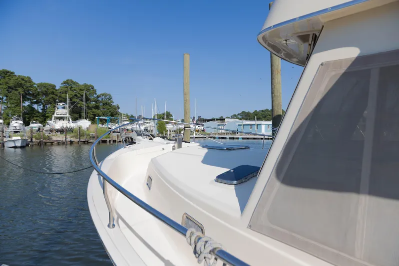 Figur'in It Out Yacht Photos Pics 2006 Mainship 400 Trawler docked at a marina, surrounded by water and trees.