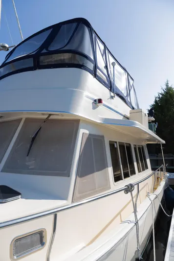 Figur'in It Out Yacht Photos Pics 2006 Mainship 400 Trawler with blue canopy, docked under clear sky.