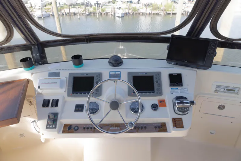 Figur'in It Out Yacht Photos Pics 2006 Mainship 400 Trawler helm with navigation equipment and steering wheel, overlooking marina.