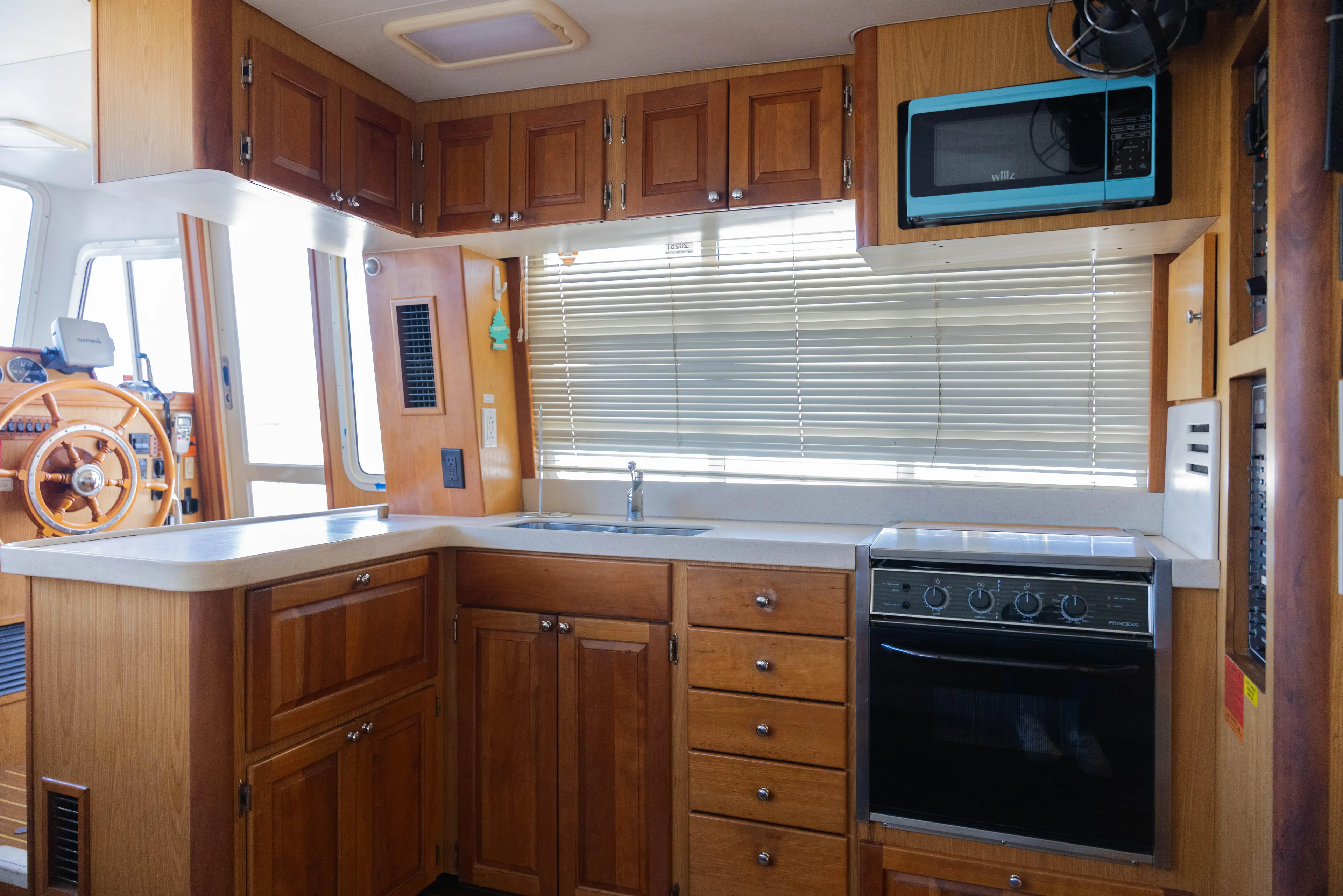 Figur'in It Out Yacht Photos Pics 2006 Mainship 400 Trawler kitchen with wooden cabinets, stove, and microwave.