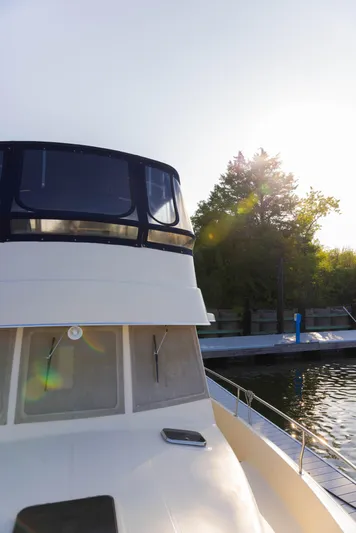 Figur'in It Out Yacht Photos Pics 2006 Mainship 400 Trawler docked, sunlit with trees in the background.