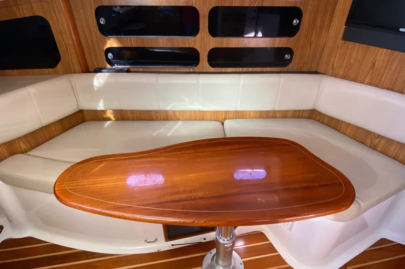  Yacht Photos Pics 2009 Pursuit OS 375 Offshore cabin with wooden table and cushioned seating.